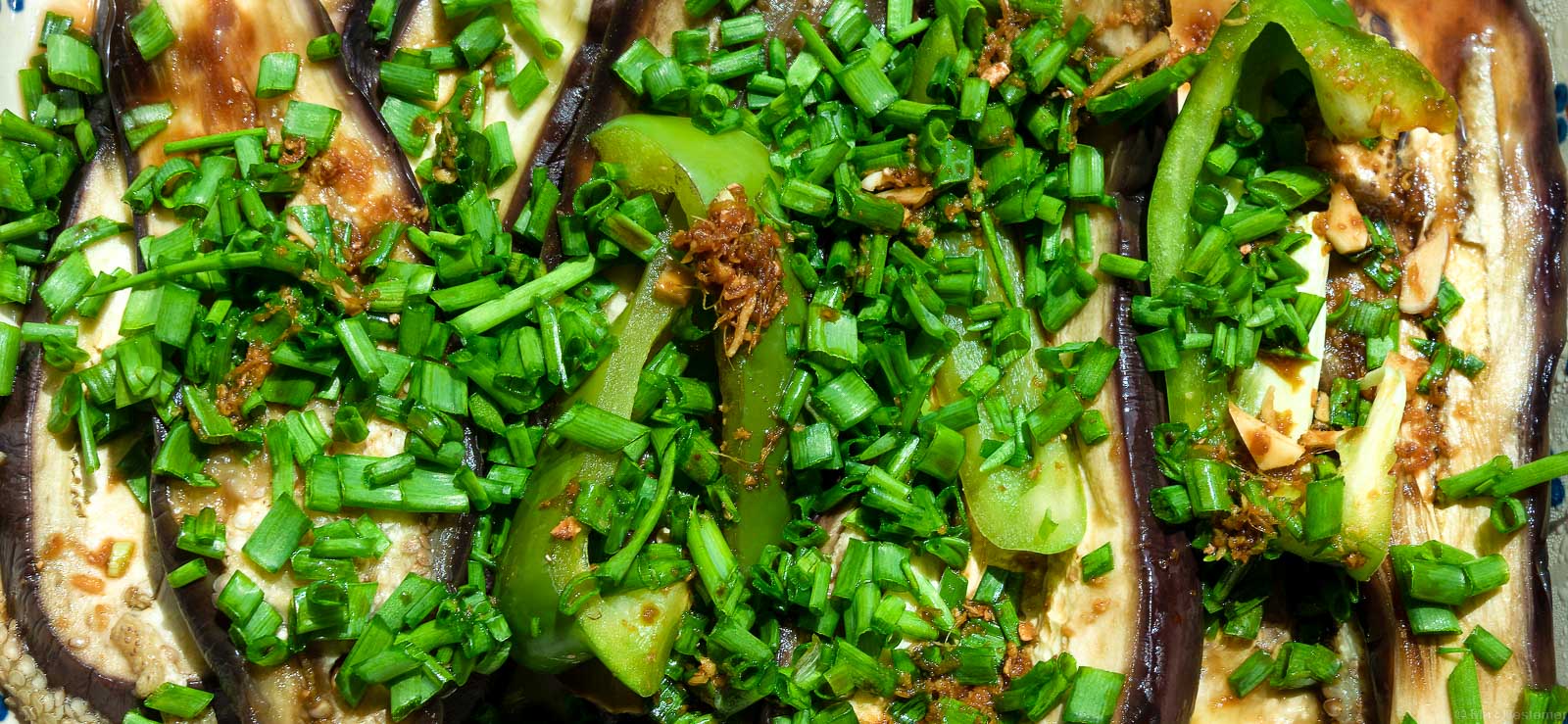 In meiner Foodfotografie habe ich diese Auberginengericht aufgenommen. Auf den geschnittenen hellen Auberginen liegt grüner Schnittlauch.